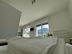 a white bedroom with a large bed and a window at Luxury Apartment SOLE in Moltrasio