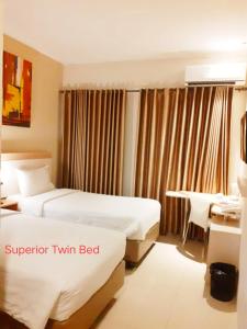 a hotel room with two beds and a desk at Laxston Hotel in Yogyakarta
