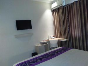 a room with a bed and a desk and a tv at Laxston Hotel in Yogyakarta