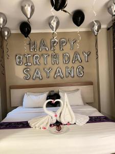 a bed with two white swans and a happy birthday sign at Laxston Hotel in Yogyakarta