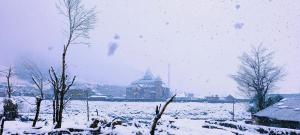 索纳马格Mitra Sonamarg的一座有雪盖的田野,后面有一座建筑