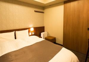 a hotel room with a large bed with white sheets at Dormy Inn Kumamoto Natural Hot Spring in Kumamoto +73 photos