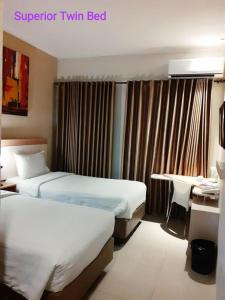 a hotel room with two beds and a desk at Laxston Hotel in Yogyakarta