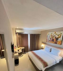 una camera d'albergo con un letto grande e una scrivania di Laxston Hotel a Yogyakarta