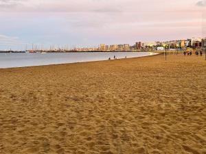 une plage de sable avec des gens marchant dans l'eau dans l'établissement Adorable urban suites, à Las Palmas de Gran Canaria 2 autres photos