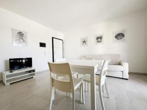 una sala da pranzo bianca con tavolo e sedie bianchi di Affittimoderni La Maddalena - MADA22 a La Maddalena