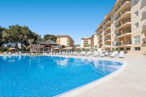 a swimming pool in a hotel with chairs and condos at Can Picafort Palace in Can Picafort