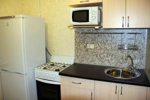 kuchnia ze zlewem, kuchenką mikrofalową i lodówką w obiekcie Apartment Ural on Evteeva 5 w mieście Czelabińsk