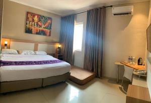 a hotel room with a large bed and a window at Laxston Hotel in Yogyakarta