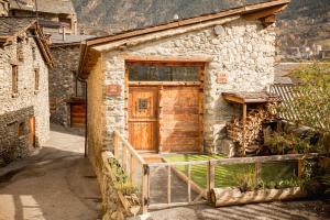 una casa in pietra con una porta in legno sul lato di R de Rural - Casa Rural de les Arnes a Encamp