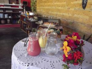 a table with two jars of juice and flowers on it at Pousada dos Mundos1 in Conde