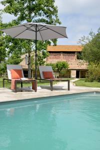 two chairs and an umbrella next to a swimming pool at CHATEAU LAURIGA in Thuir