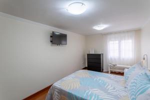 a bedroom with a bed and a tv on the wall at Ciudad Jardín Las Palmas GC in Las Palmas de Gran Canaria