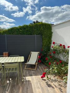 un patio con mesa, sillas y rosas rojas en Maison des Larris - proche Aéroport - navette Gare, en Beauvais