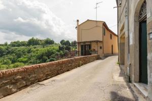 an empty road with a stone wall next to a building at Casa Il Fico in Usigliano