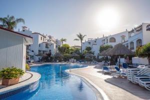 a swimming pool with chairs and umbrellas at a resort at Beautiful 4 bedroom house with phenomenal golf and mountain views in San Miguel de Abona