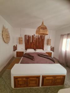 a bedroom with a large bed with a wooden headboard at La Maison des Vagues in Sidi Kaouki