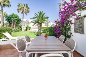 a wooden table and chairs on a patio with purple flowers at PG9 - Andalucian 3-story townhouse near Estepona in Estepona