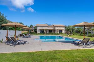 a pool with chairs and umbrellas next to a house at YANNIS RETREAT in Lefkada