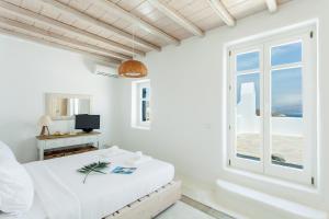 biały pokój z łóżkiem i oknem w obiekcie Villa Jasper by Mykonos Stays w mieście Mykonos