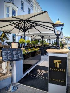 a patio with umbrellas and flowers in a building at Tynedale Hotel in Llandudno
