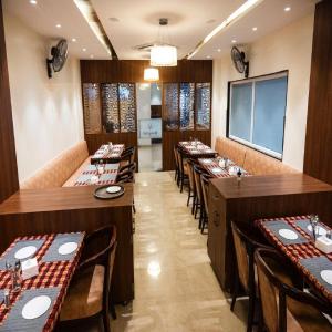 a restaurant with long tables and chairs and a screen at Hotel Kunal Palace in Ahmadnagar