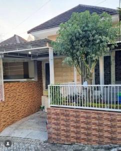a brick house with a white fence and a tree at Villa Batu Permata Garden in Malang