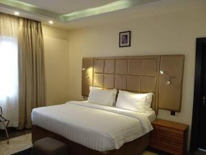 una camera da letto con un letto grande con lenzuola e cuscini bianchi di Mulligan Hotel a Lagos