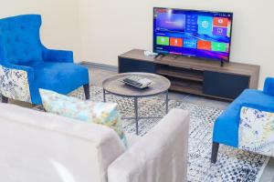 Una sala de estar con dos sillas y un televisor. en Stylish Self Catering Unit in Maseru CBD, en Maseru