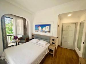a bedroom with a large white bed and a window at Carikci Hotel in Marmaris