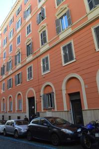 un edificio anaranjado con coches estacionados frente a él en TrastEver Holiday, en Roma
