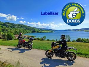 dwie osoby jadące motocyklami drogą wzdłuż jeziora w obiekcie Le p'tit Saint-Pierre - Centre ville - Parking w mieście Pontarlier