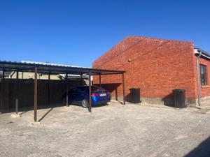 un coche aparcado en un aparcamiento junto a un edificio de ladrillo en Stylish Self Catering Unit in Maseru CBD, en Maseru
