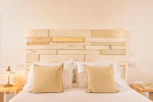 Una cama con almohadas blancas y un cabecero de madera. en Amazing apartment with swimming pool, Montepulciano Toscana, en Montepulciano