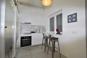 una cucina con mobili bianchi e sgabelli da bar di LA SIESTA I-14 - Fincas Arena a Benidorm