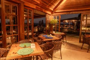 a restaurant with wooden tables and chairs and a patio at Manacá Pousada Parque in Arraial d'Ajuda