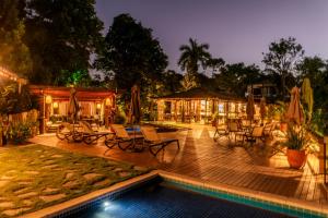 a patio with chairs and a pool at night at Manacá Pousada Parque in Arraial d'Ajuda