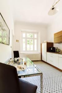 a living room with a glass table and a kitchen at Golf Apartment Villa Elisabeth in Mariánské Lázně