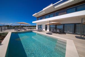 a swimming pool in front of a house at Luxury villa del Sol in Novalja