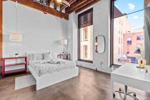 a white bedroom with a bed and large windows at Stylish Riverfront Loft- Gym - Walk to Arch, Casino, Conventions in Saint Louis