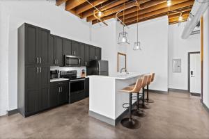a kitchen with black cabinets and a white counter top at Stylish Riverfront Loft- Gym - Walk to Arch, Casino, Conventions in Saint Louis