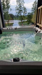 a bath tub filled with water with a view of a lake at Dom nad jeziorem Mazury - Pod Napięciem 2 in Mrągowo