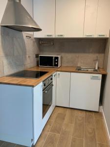 una cucina con armadietti bianchi, piano cottura e forno a microonde di T2 proche des 2 Jumeaux a Hendaye