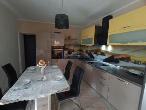 a kitchen with a table and chairs and a kitchen with yellow cabinets at Âme de la nature in Nedeščina