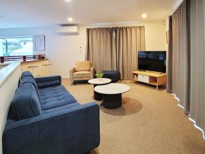 a living room with a blue couch and a tv at Sea view 5 bedroom holiday house in Whangaparaoa