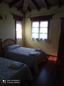 a bedroom with two beds and two windows at Casa Rural Llendelriu in Villahormes