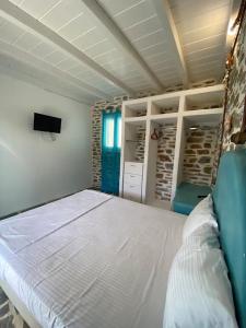a bedroom with a large white bed and a television at Acta Apartment in Kithnos