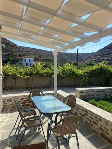 a patio with a table and chairs under a white umbrella at Acta Apartment in Kithnos