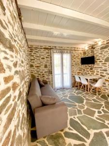 a living room with a couch and a stone wall at Acta Apartment in Kithnos