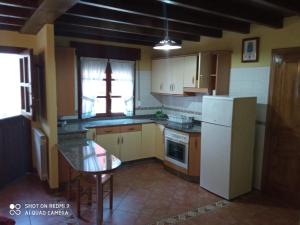 a kitchen with a white refrigerator and a table at Casa Rural Llendelriu in Villahormes
